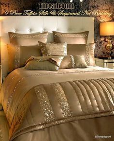 there is a bed with gold and silver sheets on it, along with two lamps