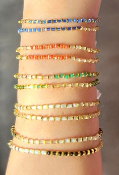 a close up of a person's arm wearing bracelets with different colored stones