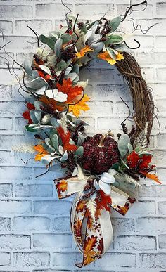 a wreath on a brick wall decorated with autumn leaves