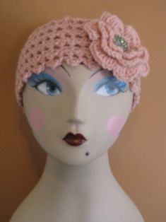 a mannequin head wearing a pink crochet hat with flowers on it