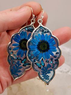 Beautiful pressed wildflower earrings in Blue. Each flower was carefully placed using a toothpick and patience. Tiny blue butterflies and blue crushed glass added for style. Extra large in size.  Sterling silver French earring wires. Hypoallergenic.  These can be made in a variety of colors. If you would like to have a pair custom made, send me a message.  Ships on an earring card with a plastic protective cover. Perfect Dark, Crushed Glass, Earring Cards, Pink Rhinestones, Blue Butterfly, Dark Pink, Purple Flowers, Dried Flowers, Hippie Boho