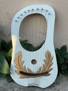 a white and gold instrument sitting on top of a cement ground next to green plants