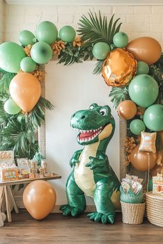 an inflatable dinosaur is sitting next to some balloons and other decorations on the wall