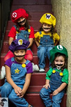 four children wearing mario bros costumes sitting on steps with their faces painted in different colors