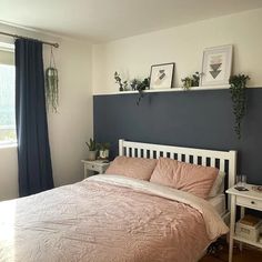 a bed sitting in a bedroom next to a window with blue curtains and potted plants on top of it