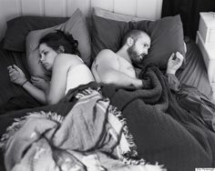 black and white photo of two people laying in bed with blankets on top of them