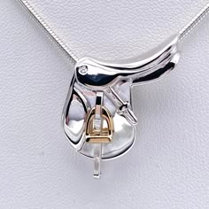 a white leather surface with a silver and gold pendant hanging from it's side