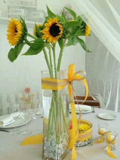 a vase filled with sunflowers sitting on top of a white tablecloth covered table