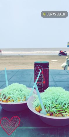 two plates with noodles and drinks on the beach