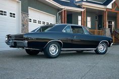 an old black car parked in front of a house