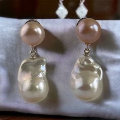 New double pearl earrings with peach pearl stud! This handmade peach and white Pearl earrings is classic and elegant.  The Baroque or flameball cultured dangling pearls are large, see photos for exact measurements, white; lustrous, AAA quality.  The pearl is attached to a sterling silver peg/bail, connected to a beautiful genuine peach, large, Freshwater button Pearl stud, silver stainless steel. The freshwater pearls are lustrous, measures 11mm to 12mm.  Comes with large, sturdy ear nuts.   Jus High Luster Drop Pearl Earrings, Pink Teardrop Pearl Earrings For Formal Occasions, Pink Drop Pearl Earrings For Formal Occasions, High Luster Pearl Drop Earrings, Elegant Apricot Earrings For Gift, Elegant Apricot Jewelry For Wedding, Pearl White High Luster Pear Shaped Pearl Earrings, Pink Dangle Pearl Earrings For Formal Occasions, Baroque Pearl White Pearl Earrings For Party