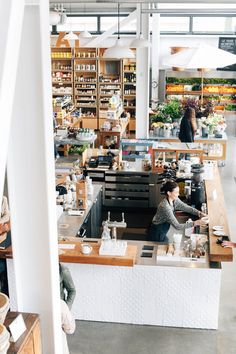 the interior of a coffee shop with people working at their desks and shelves full of items