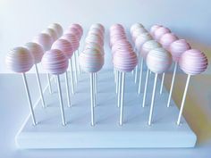 there are many pink and white cake pops on the stick in front of each other