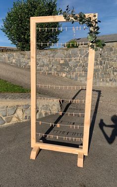 a wooden frame with clothes pegs attached to it and a tree in the background