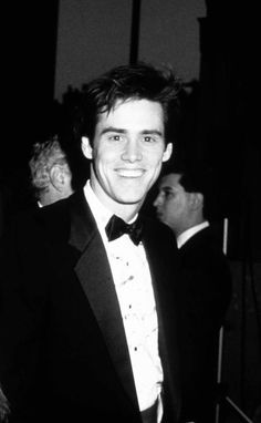 a black and white photo of a man in a tuxedo smiling at the camera