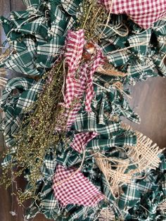 a wreath with green and red plaid ribbon hanging from the front door, on a wooden wall