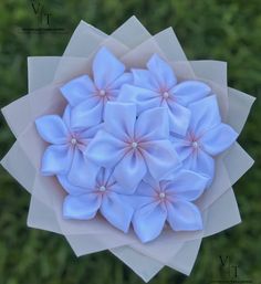 a bunch of blue flowers sitting on top of a white piece of paper in the grass