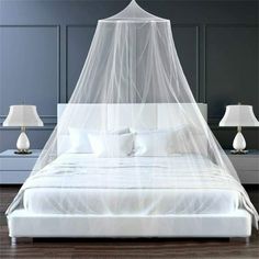 a bed with a white canopy over it and two lamps on either side of the bed