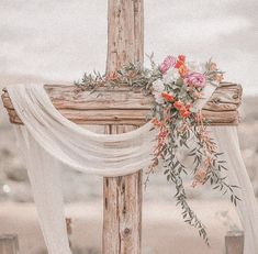 a wooden cross decorated with flowers and greenery