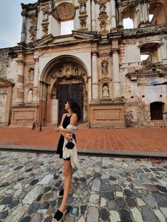 a woman is standing in front of an old building with stone floors and arches on it