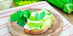 an open face sandwich with avocado and cilantro on a wooden plate