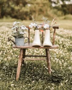 two white vases sitting on top of a wooden chair in a field filled with flowers