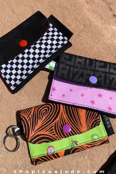 three small wallets sitting next to each other on top of a sandy surface,