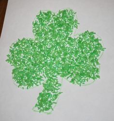 a paper with green sprinkles on it and a shamrock made out of white paper