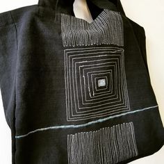 a black tote bag with an abstract design on it