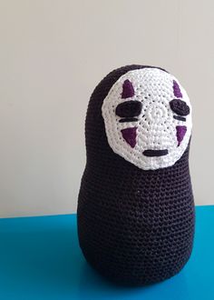 a crocheted black and white stuffed animal with purple eyes on it's head