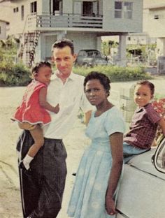 a man and two children are standing in front of a car