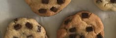 four chocolate chip cookies on a baking sheet