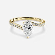 a yellow gold engagement ring with a pear shaped diamond in the center and side stones