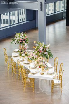 a long table with gold chairs and flowers on it