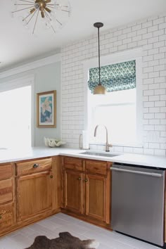 a kitchen with white brick walls and wooden cabinets, an oven, dishwasher, and sink