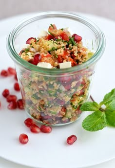 a glass jar filled with lots of food next to some green leafy leaves on the table