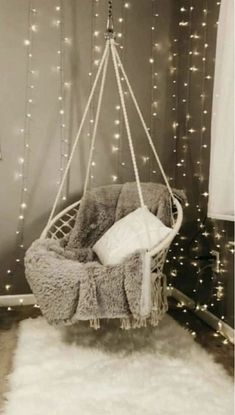 a white hanging chair in a room with lights on the wall behind it and a fluffy rug covering the floor