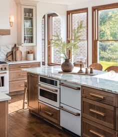 a kitchen with an oven, dishwasher, and sink in front of two windows