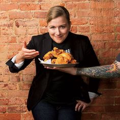 a woman holding a plate with fried chicken on it