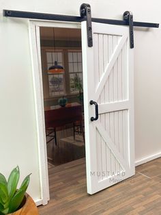 an open white door leading to a dining room with a table and potted plant