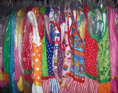 a rack full of colorful clothing hanging on clothes hangers in a closet with clear plastic bags