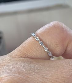 a woman's hand with a diamond ring on her left thumb and the other hand holding it