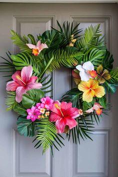 a wreath with tropical flowers and leaves on the front door