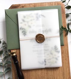 an envelope with a wax stamp on it and a bottle of wine next to it