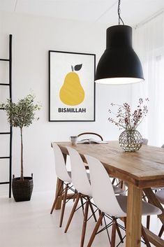 a dining room table with white chairs and a black lamp hanging over it's head