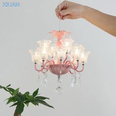 a pink chandelier hanging from the ceiling next to a potted plant