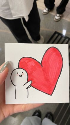 someone is holding up a card with a drawing of a heart and a person's hand