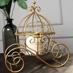 a golden birdcage on a table next to a vase