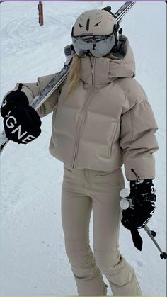 a woman is standing in the snow with skis on her shoulders and holding two ski poles