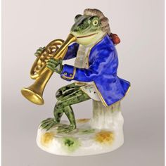 a figurine of a frog with a trumpet in his hand and wearing a blue suit